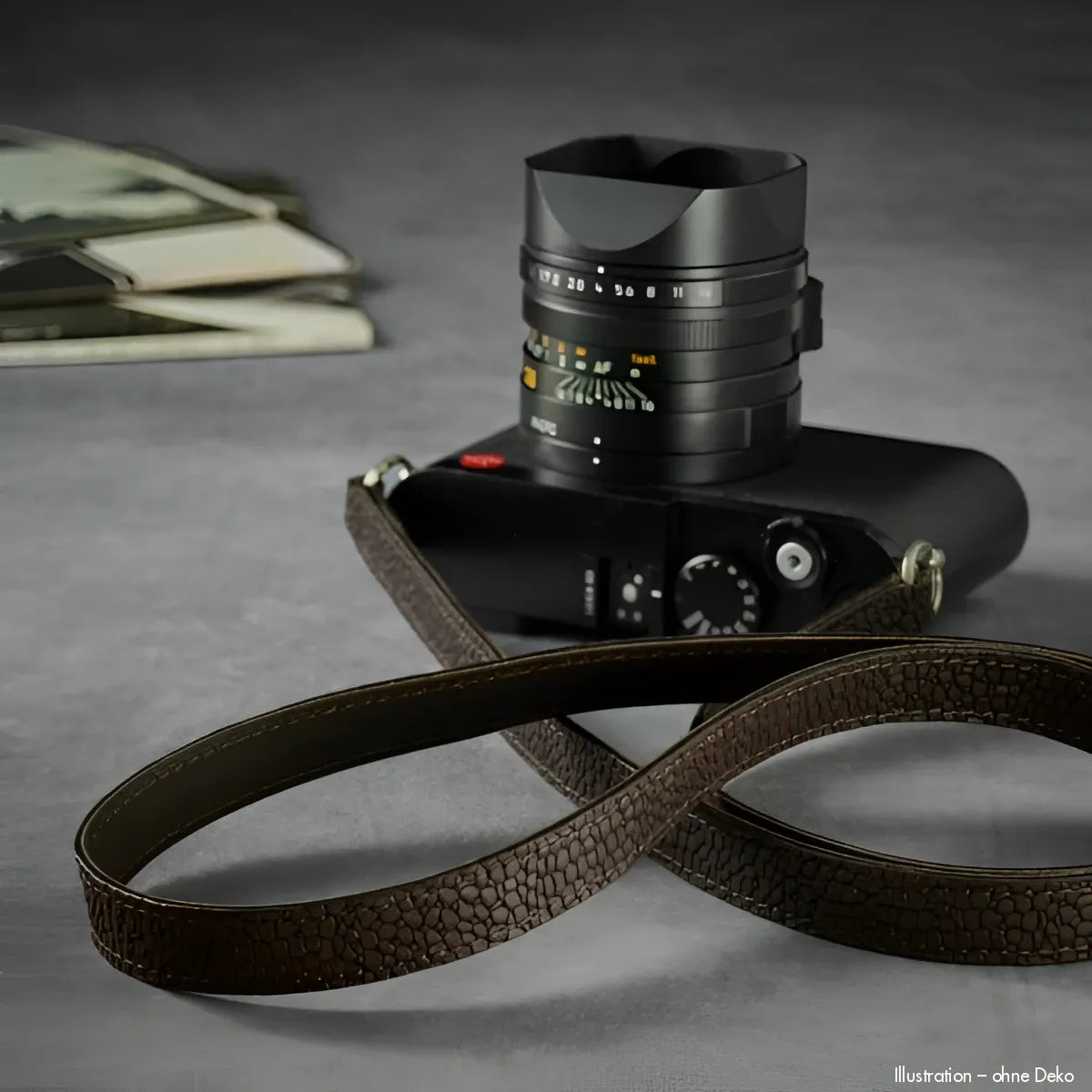 Schwarze Leica Kamera mit braunem Narbenleder-Gurt und geprägtem Objektivdeckel