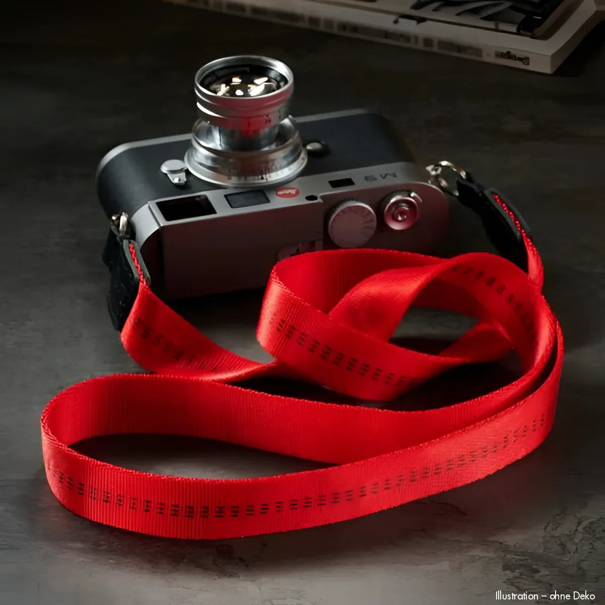 Silberne Leica Kamera mit rotem Rock N Roll Schultergurt und Blendenverschluss
